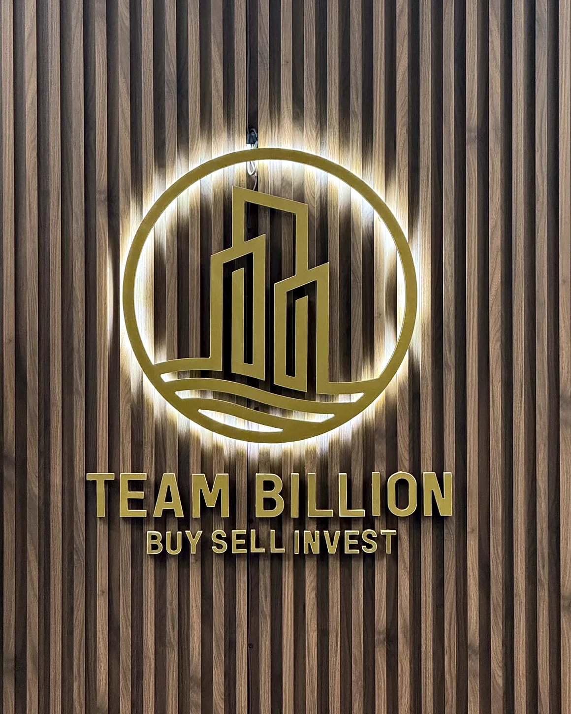 Backlit Team Billion sign on a wood slat wall in the brokerage office
